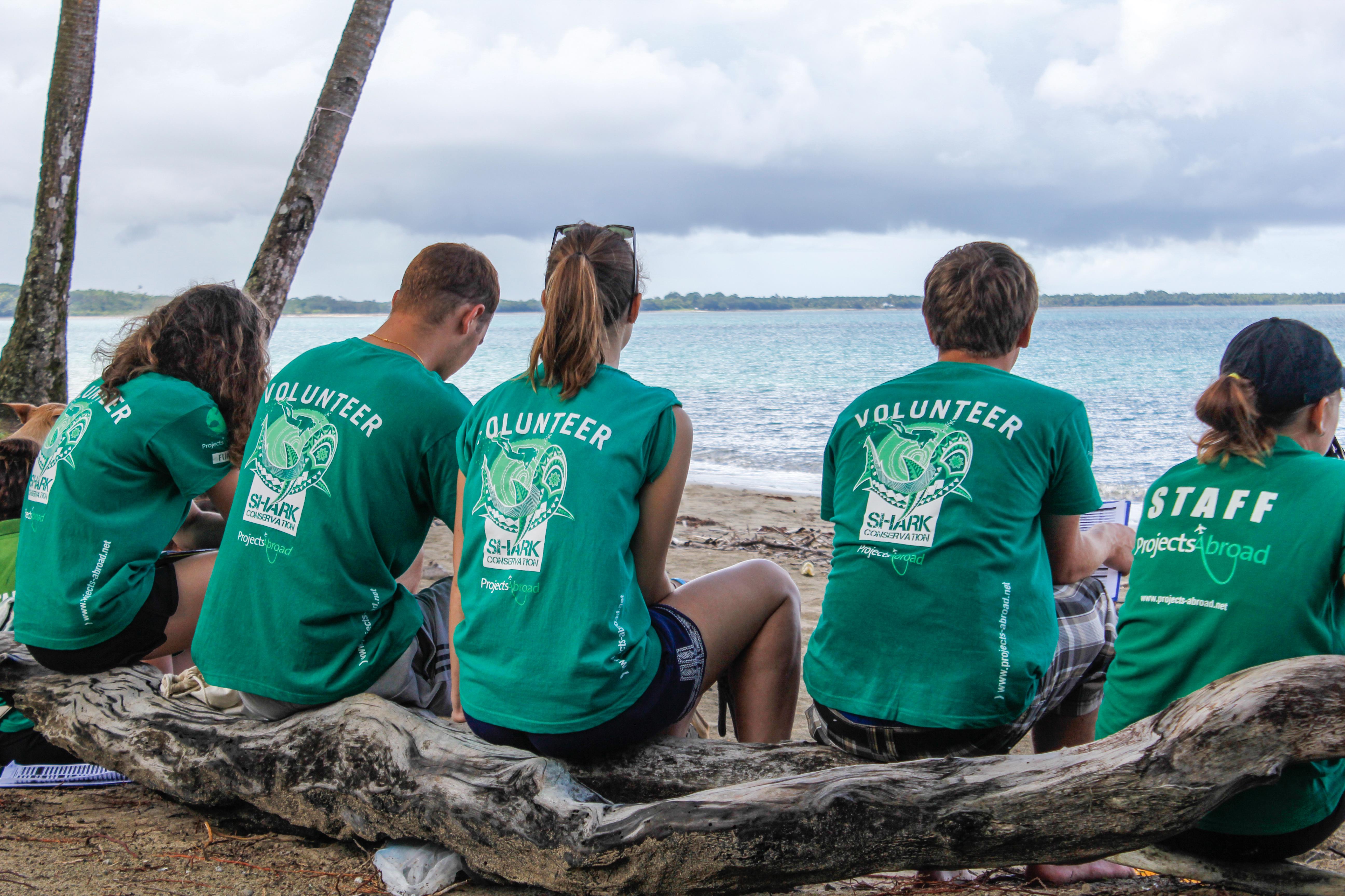 Jóvenes voluntarios tomándose un descanso de su voluntariado con tiburones en una playa de Fiyi. Voluntarios preparándose para comenzar su voluntariado ambiental para jóvenes en Fiyi.